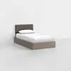 A single bed with a light wood frame, white bedding, and a dark upholstered headboard, placed in a minimal, empty room with light gray flooring and white walls.