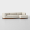A modern, L-shaped sectional sofa with light beige upholstery and a wooden base, set against a plain white background.