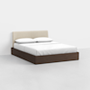 A modern bed with a dark wooden frame, a light beige upholstered headboard, and white bedding with two pillows, set against a plain white background.
