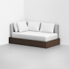 A modern daybed with a dark wooden base, light gray upholstered back and side, and four white pillows, placed against white walls in a minimalist room with a light gray floor.