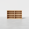 A wooden shelving unit with four open compartments, two on each side, standing on a light gray floor against a plain white background.