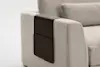 A close-up of a beige fabric sofa with a dark brown leather armrest organizer draped over the arm, featuring a large pocket.
