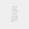A pair of cream-colored ribbed socks neatly folded, wrapped with a white band labeled THUMA, set against a plain white background.