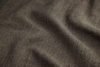 Close-up of brown textured fabric with a visible woven pattern and gentle folds, creating soft shadows and highlighting the material’s tactile surface.