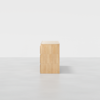 A light wood chest of drawers viewed from the side, showing its rectangular shape and smooth, minimalist design, set against a plain white background.