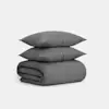 Two gray textured pillows are stacked on top of a neatly folded matching gray blanket, all set against a plain white background.