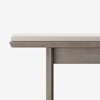 A close-up of a wooden bench with a light gray cushioned seat, shown against a plain white background. The bench has clean, modern lines and a smooth finish.