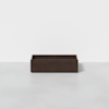 A rectangular, dark brown wooden box with an open top sits on a light gray floor against a plain white background.