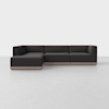 A modern, dark gray L-shaped sectional sofa with clean lines and a low profile, set on a light wooden base, positioned in a minimalist, light-colored room.