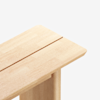 A close-up of a light wooden table with a groove running down the center, set against a plain white background.