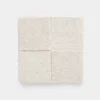 A square, light beige textured fabric swatch divided into four equal sections, each with a slightly different pile direction, placed on a plain white background.