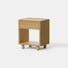 A modern wooden nightstand with a single drawer and an open shelf below, standing on four short legs against a plain white background.