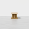 A minimalist wooden square table with a central support and a flat base, set against a plain white background.