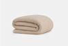 A neatly folded, beige textured blanket placed on a plain white background.