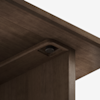 Close-up view of a dark wooden table corner showing a recessed screw embedded in the underside of the tabletop where it meets the leg, highlighting the joinery and hardware detail.