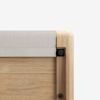 Close-up of the corner of a wooden furniture piece with a light beige fabric panel and rounded edges, featuring two visible black screws against a plain white background.