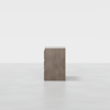 A minimalist, three-drawer wooden dresser in a light brown finish is centered on a seamless, light gray background, viewed directly from the front.