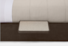 A close-up of a bed with a beige comforter and a built-in rectangular platform attached to the dark wooden bed frame, possibly serving as a small side table or shelf.