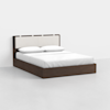 A modern bed with a dark wooden frame, low profile, and a rectangular headboard featuring a padded cream-colored panel. The bed is neatly made with white bedding and pillows.