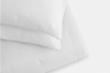 Two white, textured pillows stacked on top of each other against a plain white background.