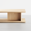 A minimalist wooden coffee table with a rectangular top and base, connected by a vertical central panel, set against a plain white background.
