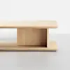A minimalist wooden coffee table with a rectangular top and base, connected by a vertical central panel, set against a plain white background.