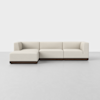 A modern, L-shaped sectional sofa with light beige upholstery and a dark wooden base, set against a plain white background.