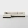 A modern, L-shaped sectional sofa with light beige upholstery and a dark wooden base, set against a plain white background.