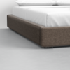 Close-up of the corner of a modern bed frame with a dark upholstered base, white bedding, and a light grey floor.
