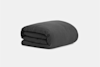 A neatly folded dark gray comforter or blanket, placed on a plain light background.