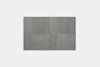 A square patchwork of four textured, gray carpet tiles is displayed against a plain, light gray background.