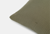 A close-up of a textured green pillow with a subtle square grid pattern, shown against a plain white background.