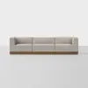 A modern beige three-seat sofa with low backrests and arms, set on a wooden base, positioned against a plain white background.