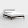 A modern bed with a light gray upholstered headboard, white bedding, and two pillows sits on a dark wooden frame in a minimal, white-walled room.