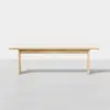 A simple, rectangular wooden bench with clean lines and a light natural finish, set against a plain white background.