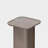 A minimalist, square-topped, light brown wooden pedestal with rounded edges against a plain white background.