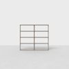 A minimalist, light-brown wooden shelving unit with six open rectangular shelves, standing on a smooth, light gray floor against a plain white background.