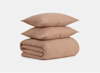 Two beige textured pillows stacked on top of a matching folded blanket, set against a plain white background.