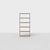 A simple, empty wooden bookshelf with five shelves stands against a plain, light gray background and floor.