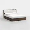 A modern platform bed with a dark wood frame, a beige upholstered headboard, and white bedding with two pillows, placed in a minimal, white-walled room.