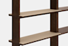 A close-up view of a wooden shelving unit with light-colored shelves and dark vertical supports, photographed against a plain white background.