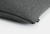 A close-up of a dark gray fabric cushion with a visible black zipper and a small black tag labeled WMWM on a white surface.
