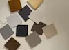 A selection of fabric swatches in neutral colors and four wood samples are arranged on a beige surface, showcasing different textures and finishes.