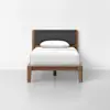 A single wooden bed with a dark gray upholstered headboard, white bedding, and a white pillow, set against a plain white background.