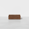 A rectangular wooden storage box with a simple design sits on a light gray floor against a plain white background.