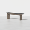 Modern wooden bench with a dark cushioned seat and simple rectangular legs, placed on a light, plain surface with a white background.