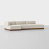 A modern, low-profile sectional sofa with light beige upholstery and a wooden base, set against a plain white background. The sofa features clean lines and a left-facing chaise lounge.