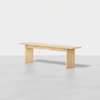 A simple, modern wooden bench with clean lines and a natural finish, placed on a light gray floor against a plain white background.