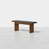 A modern wooden bench with a dark cushioned seat and simple, clean lines, set against a plain white background.