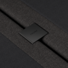 Close-up of a textured, dark gray fabric with a black, rectangular tag in the center that reads THUMA in uppercase letters.